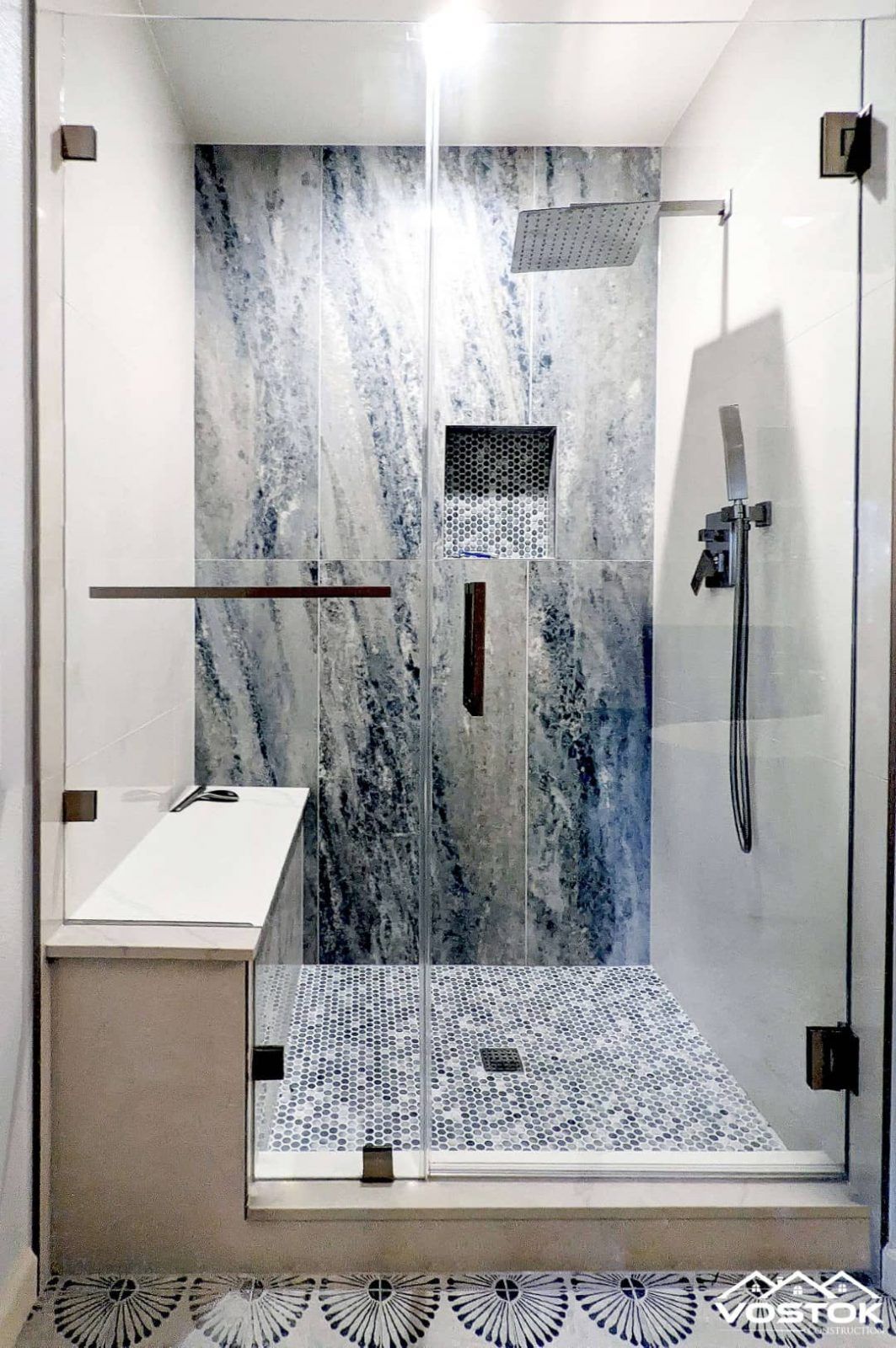 A bathroom with a walk in shower and a bench.