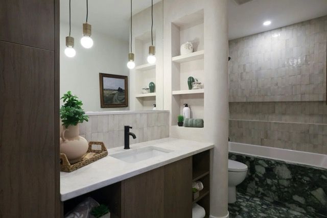 Beautiful and modern bathroom with green tile floor, plants, and wood cabinets