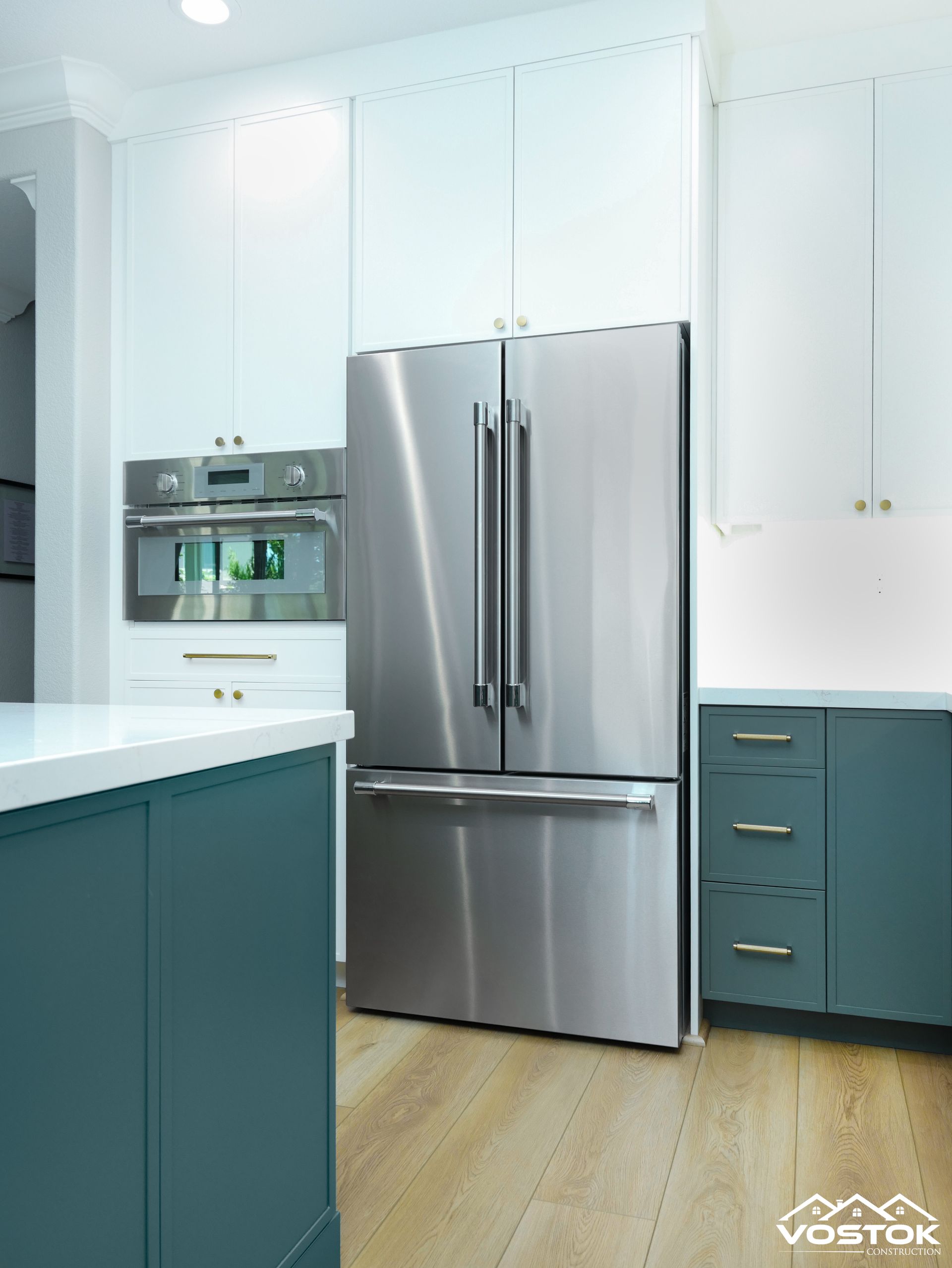 A stainless steel refrigerator in a kitchen with blue cabinets