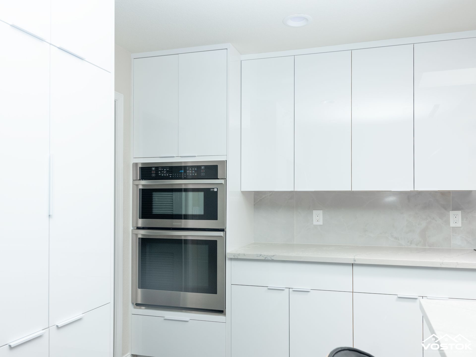 A kitchen with white cabinets and a stainless steel oven.