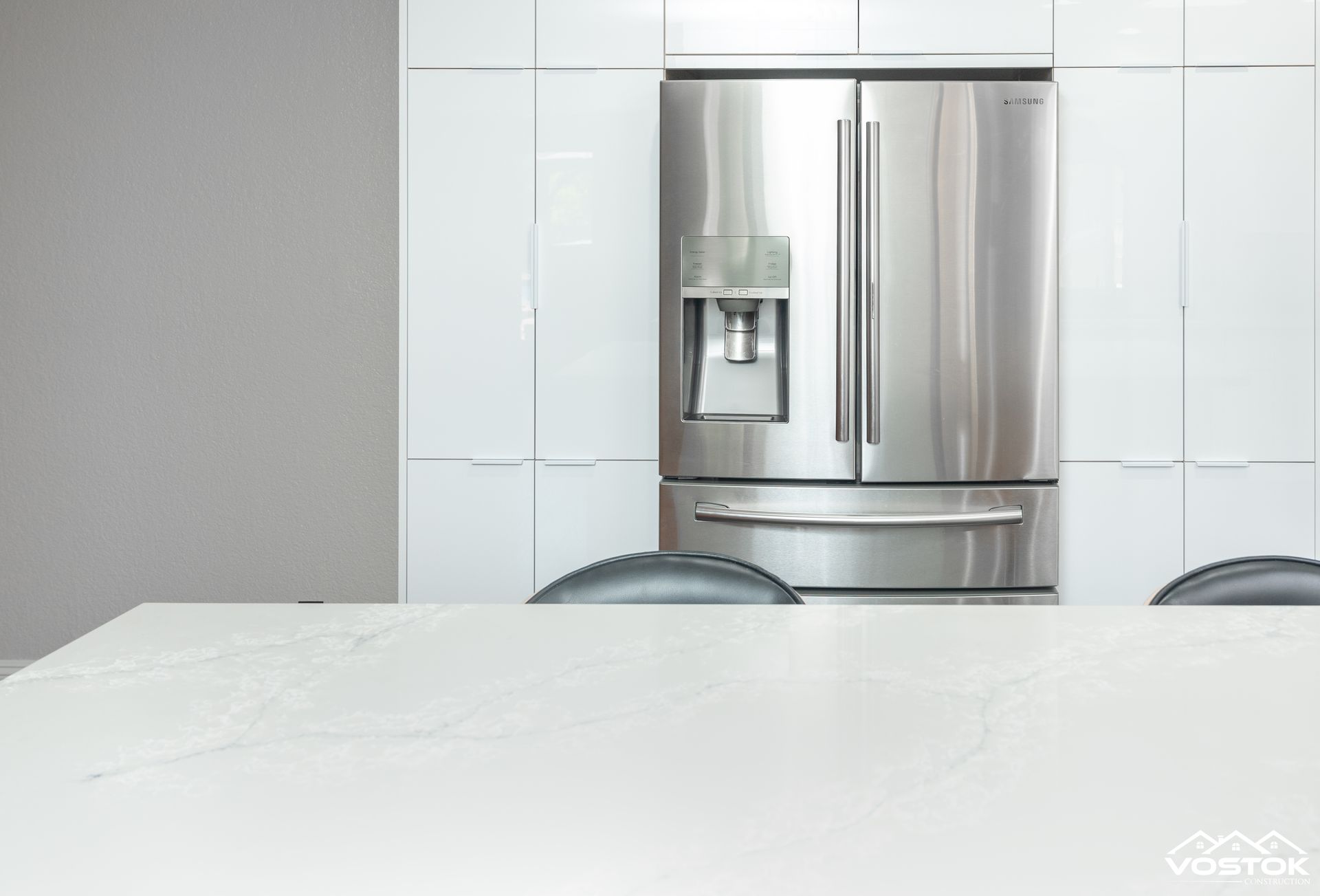 A stainless steel refrigerator is sitting on top of a white counter in a kitchen.