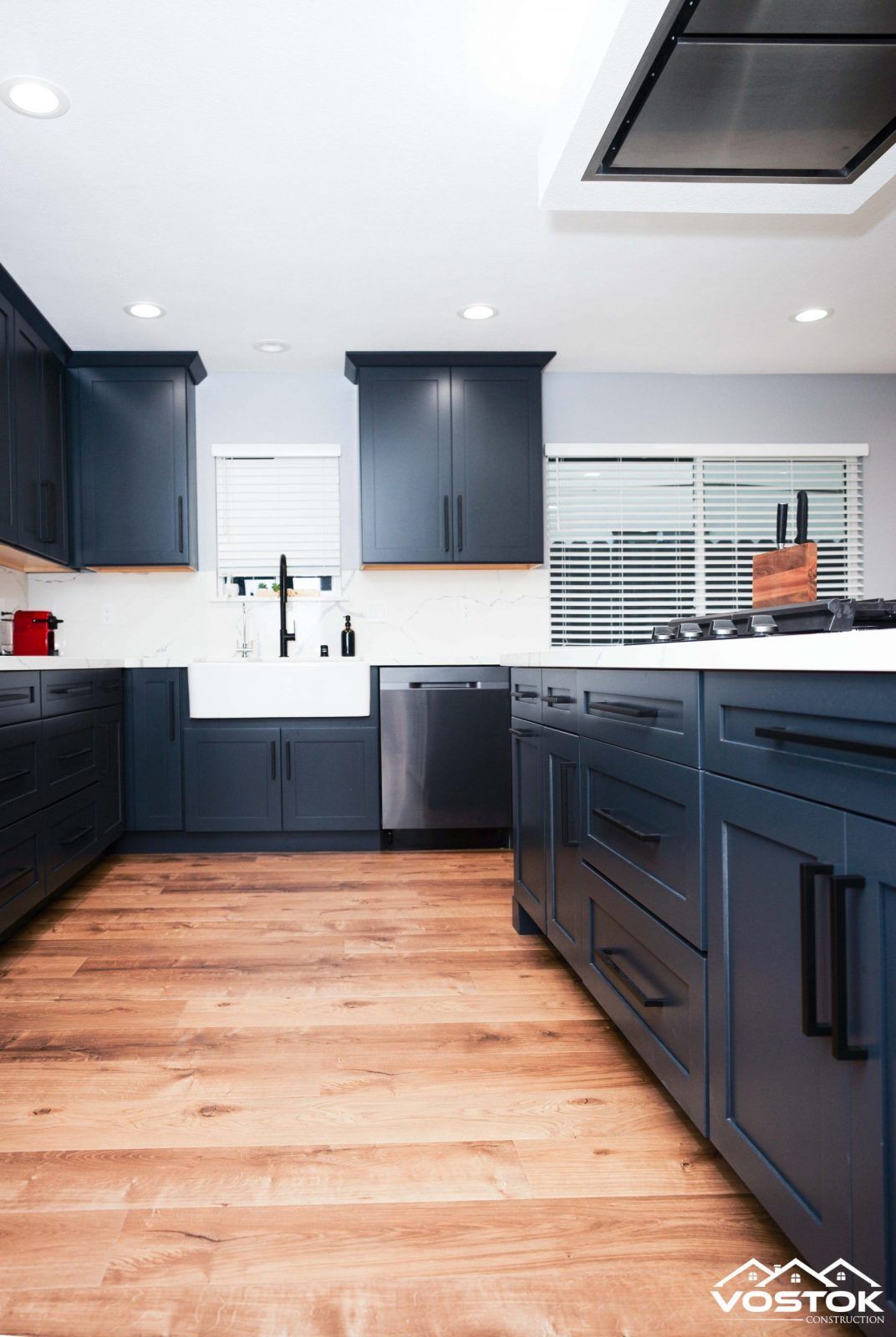 A kitchen with blue cabinets and wooden floors.