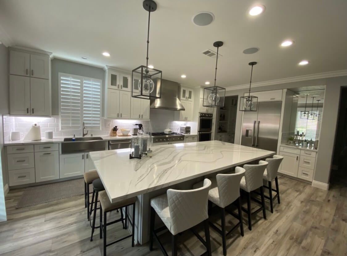 A kitchen with a large island and stools in it.