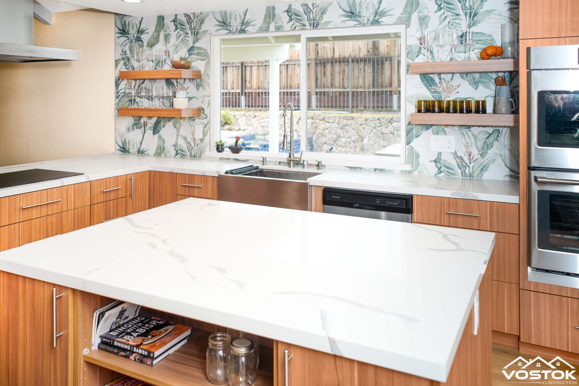 A kitchen with wooden cabinets , white counter tops , stainless steel appliances and a large island.