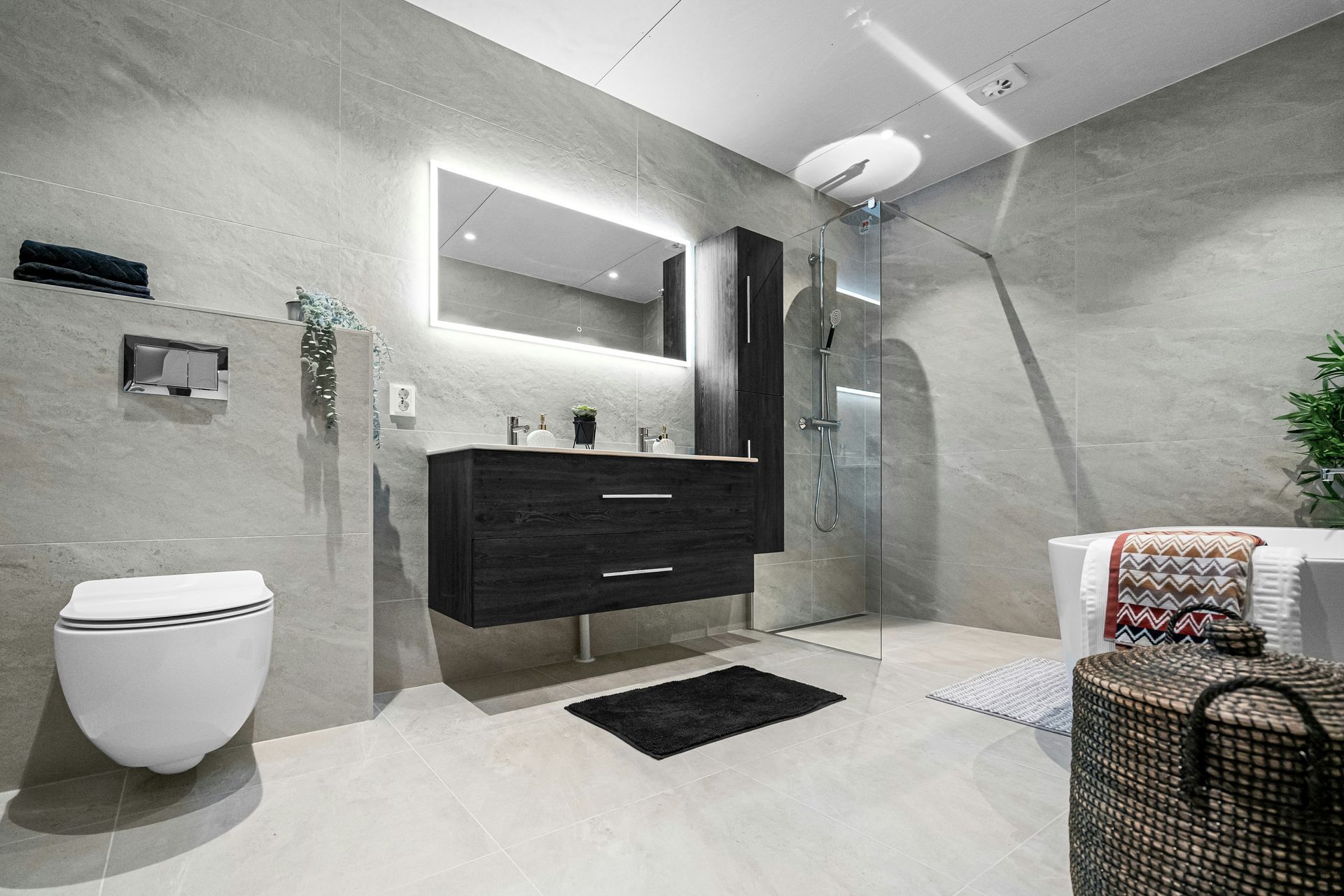 A bathroom with a toilet , sink , mirror and walk in shower.