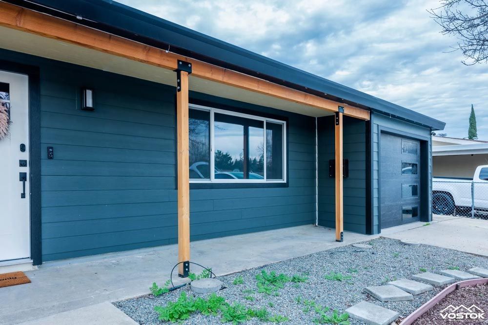 A blue house with a white door and a white truck parked in front of it.
