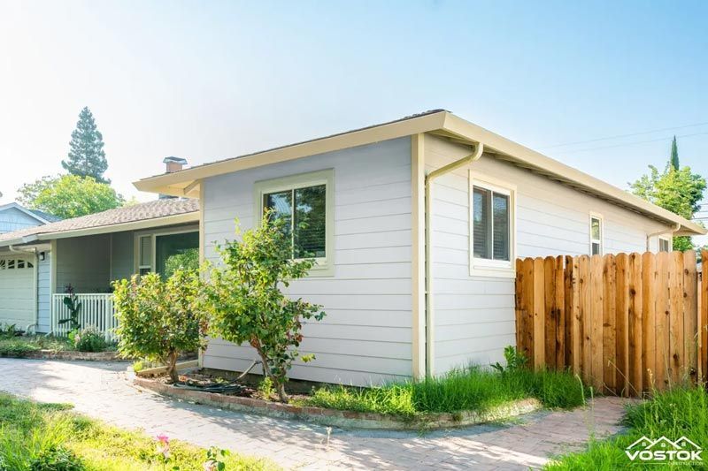 A small white house with a wooden fence in front of it.