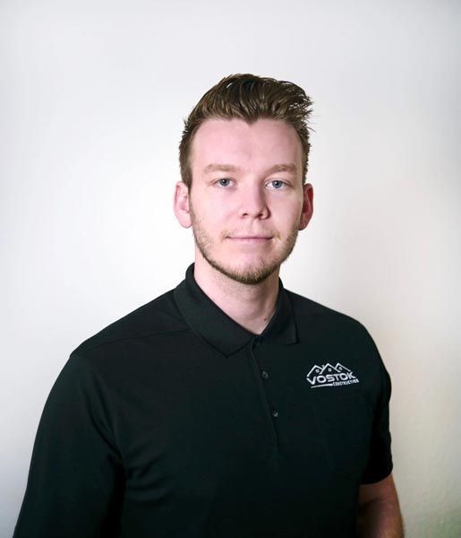 A man with a beard is wearing a black polo shirt.