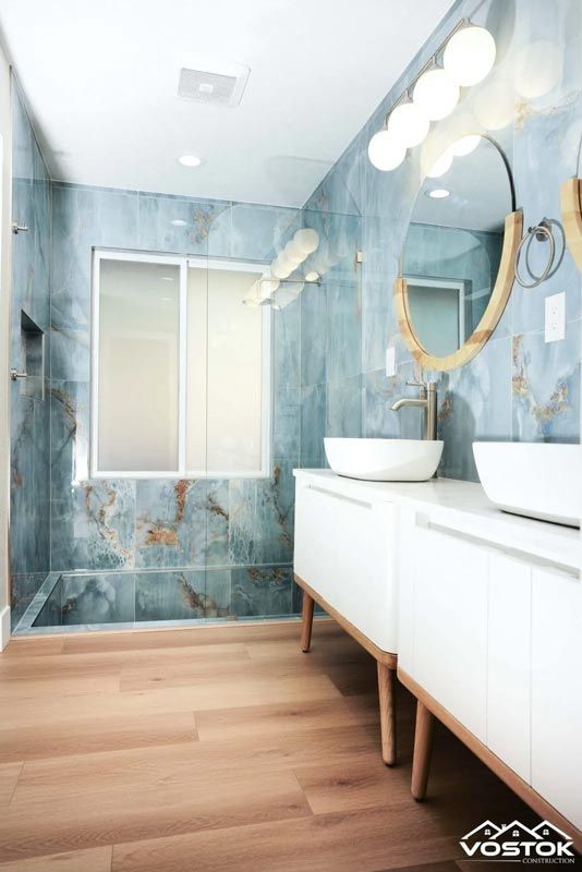 A bathroom with two sinks , a mirror and a walk in shower.