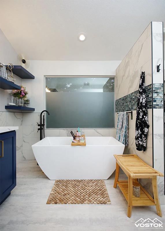 A bathroom with a bathtub , sink , and bench.