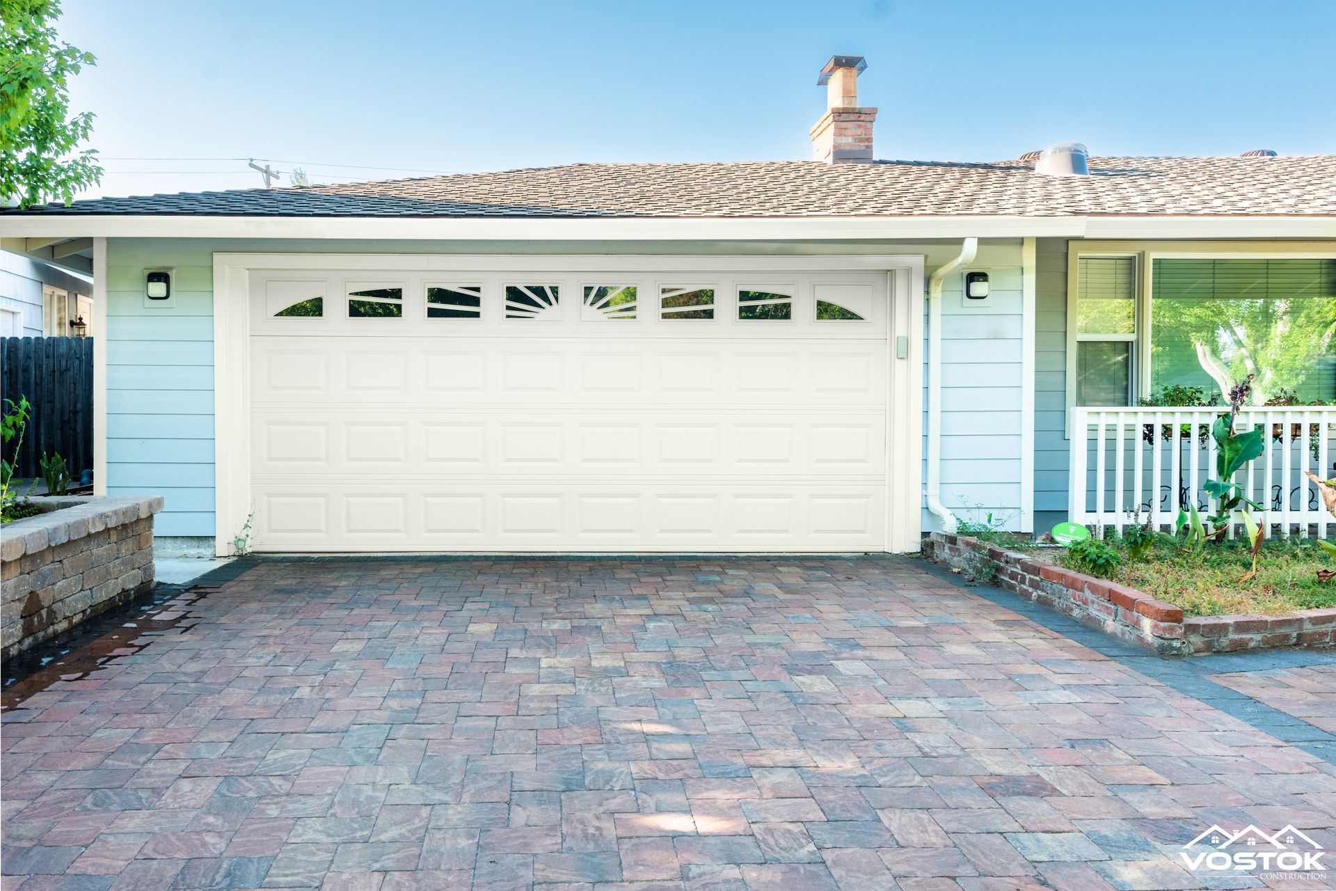 A house with a white garage door and a brick driveway.