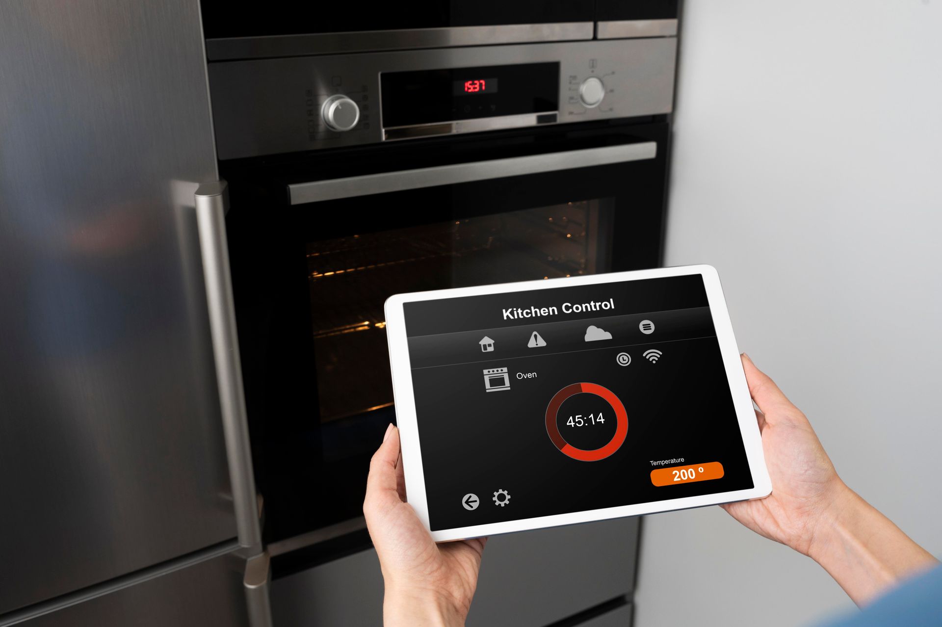 Woman holding tablet to control smart kitchen oven