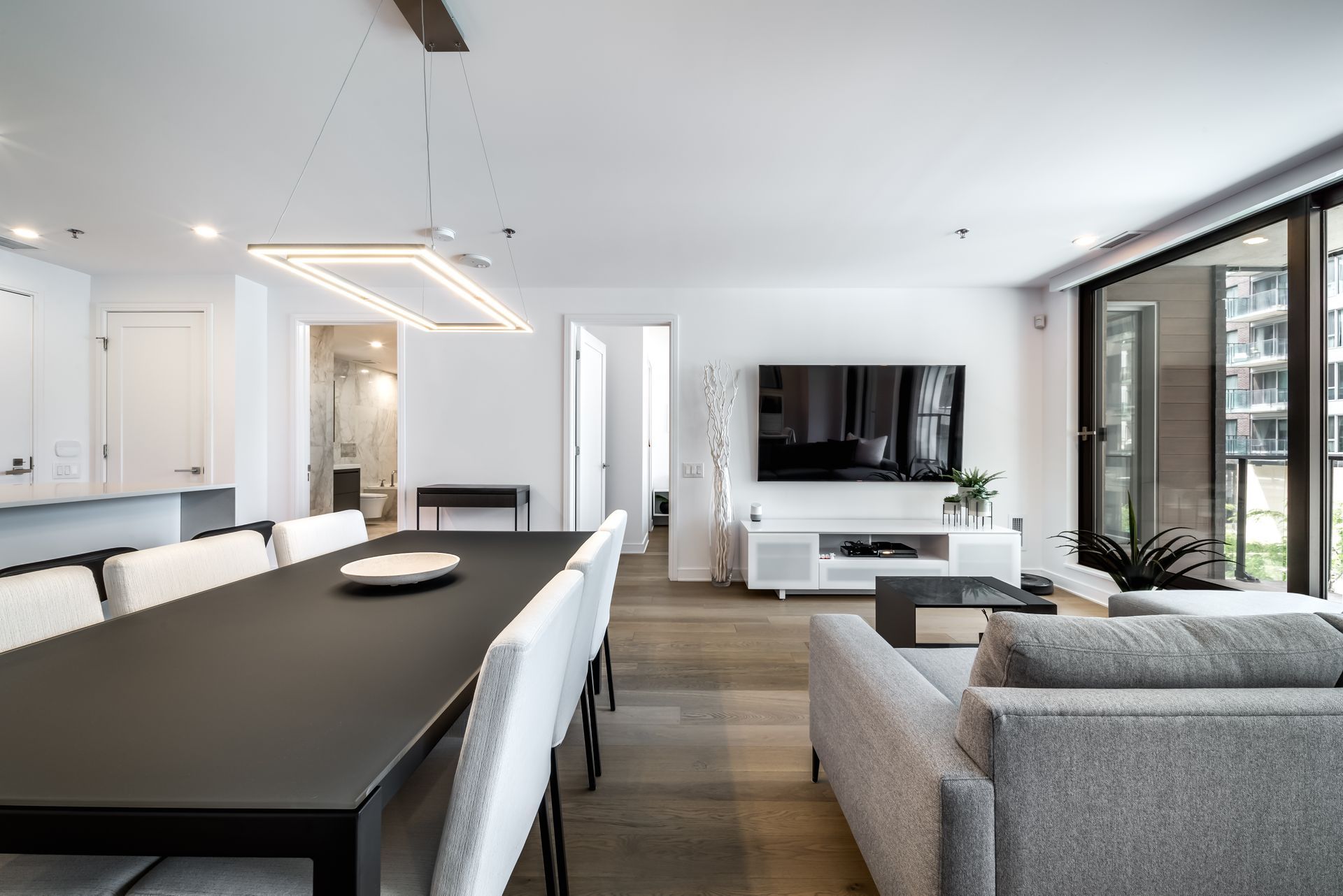 A modern open‑concept living and dining area with wood floors and large windows.