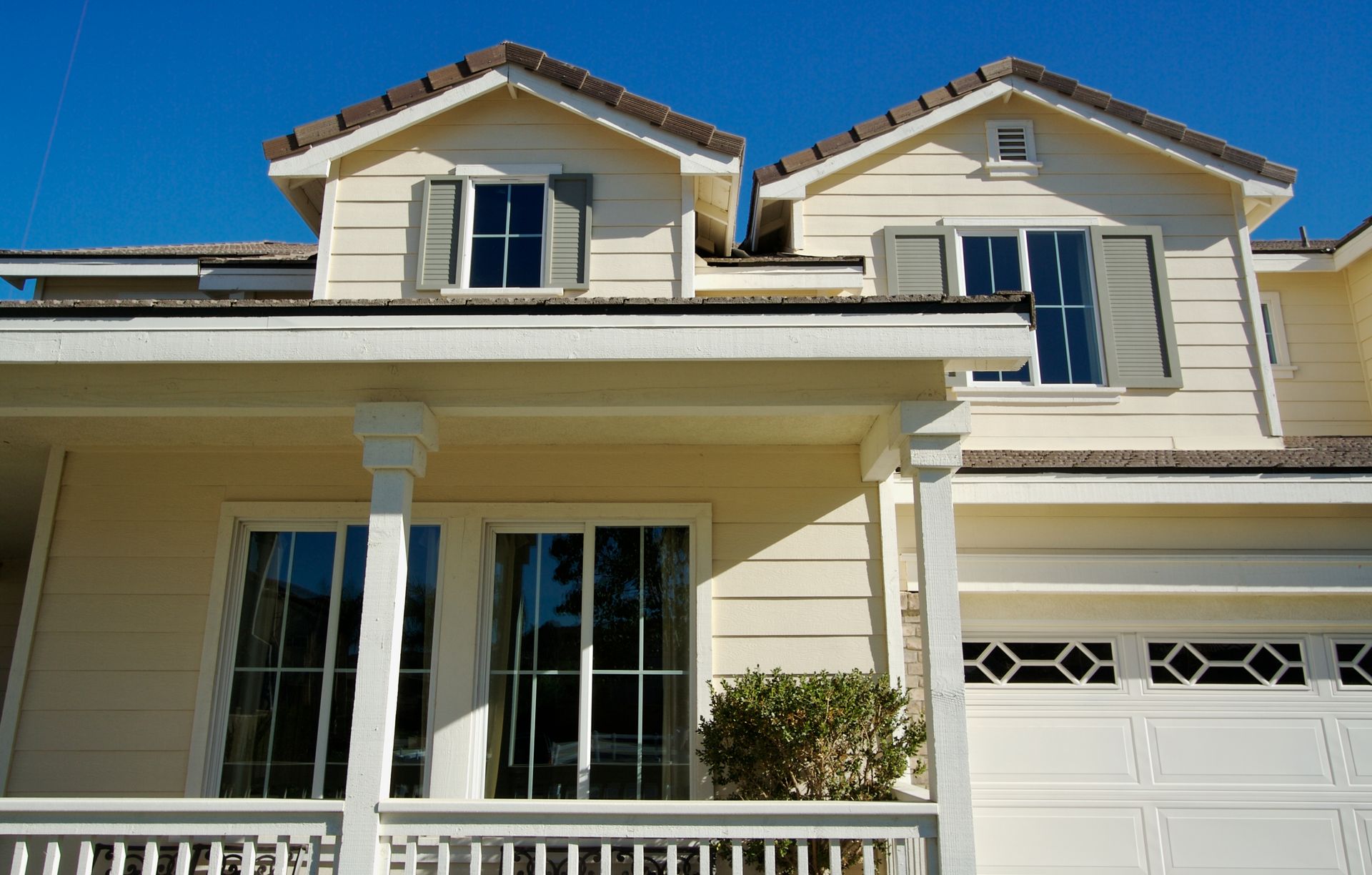 Yellow home with a porch, garage door, windows and siding