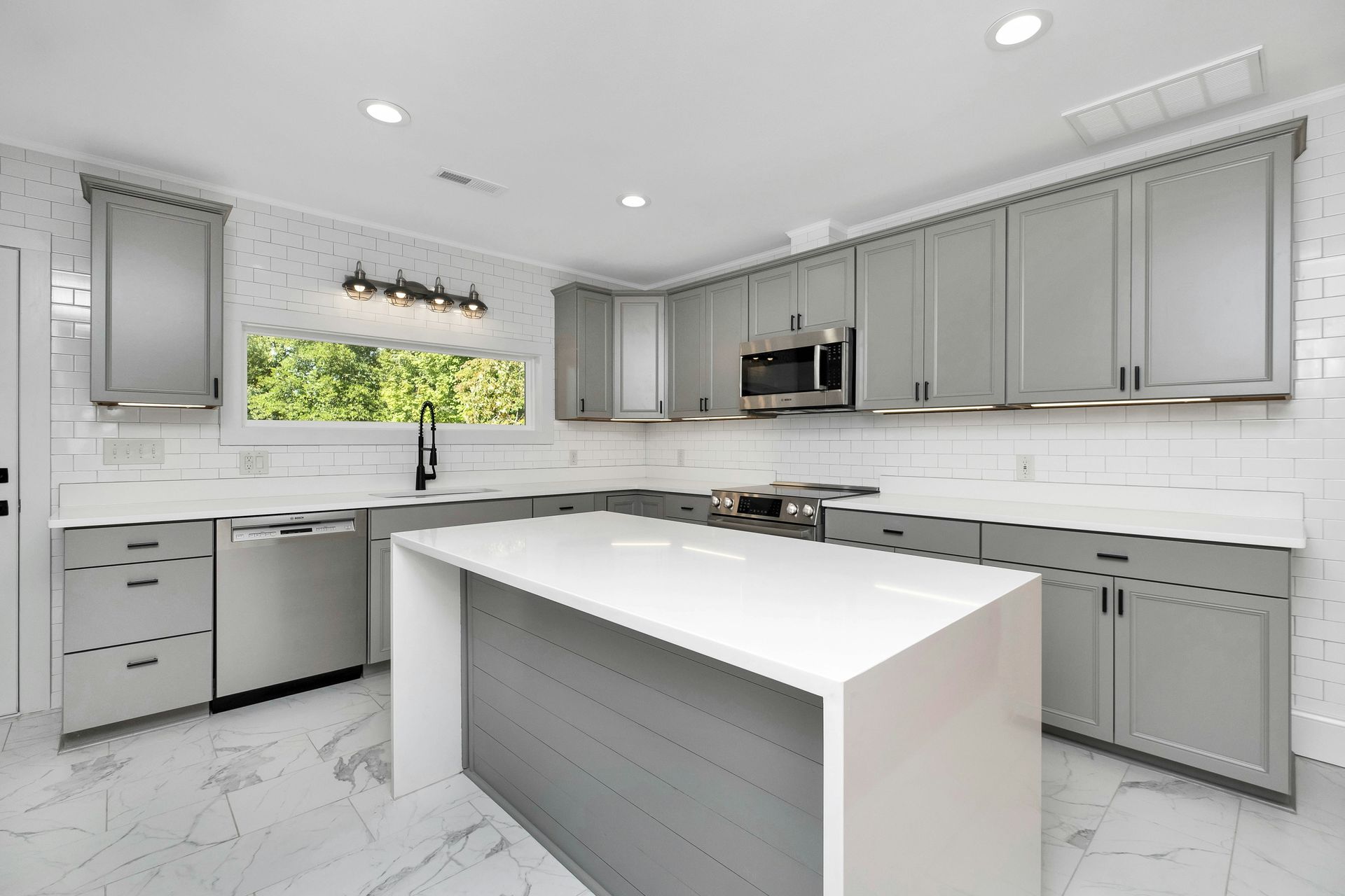 A kitchen with grey cabinets and white countertops