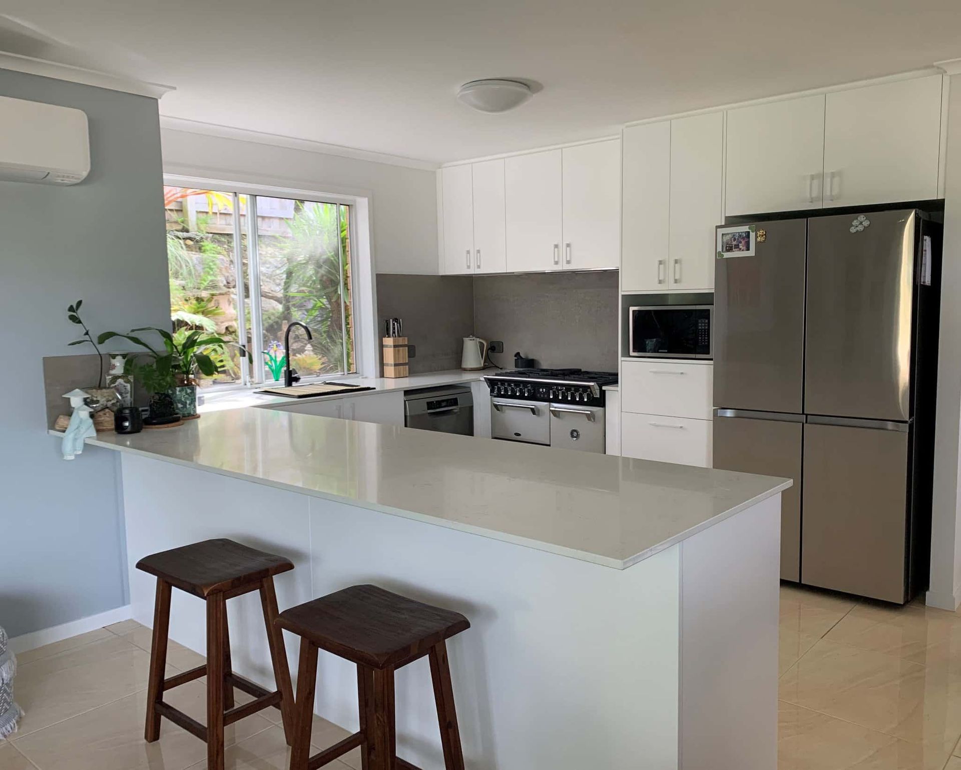 A Kitchen With Bench And Two Stools With Fridge Stove And Sink