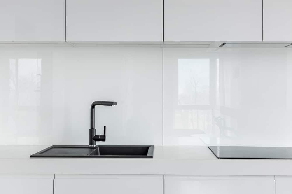 A Kitchen With White Cabinets, A Black Sink, And A Black Stove Top Oven — South East Kitchens In Burleigh Heads, QLD