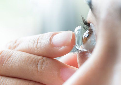 young woman inserting contact lens