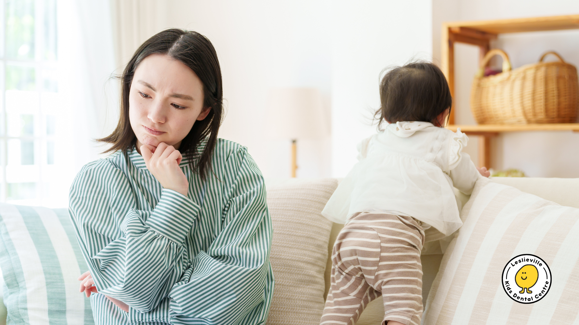 A woman is sitting on a couch with a baby standing next to her.