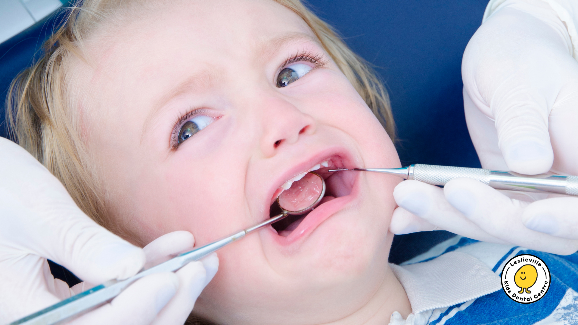 A little girl is getting her teeth examined by a dentist.