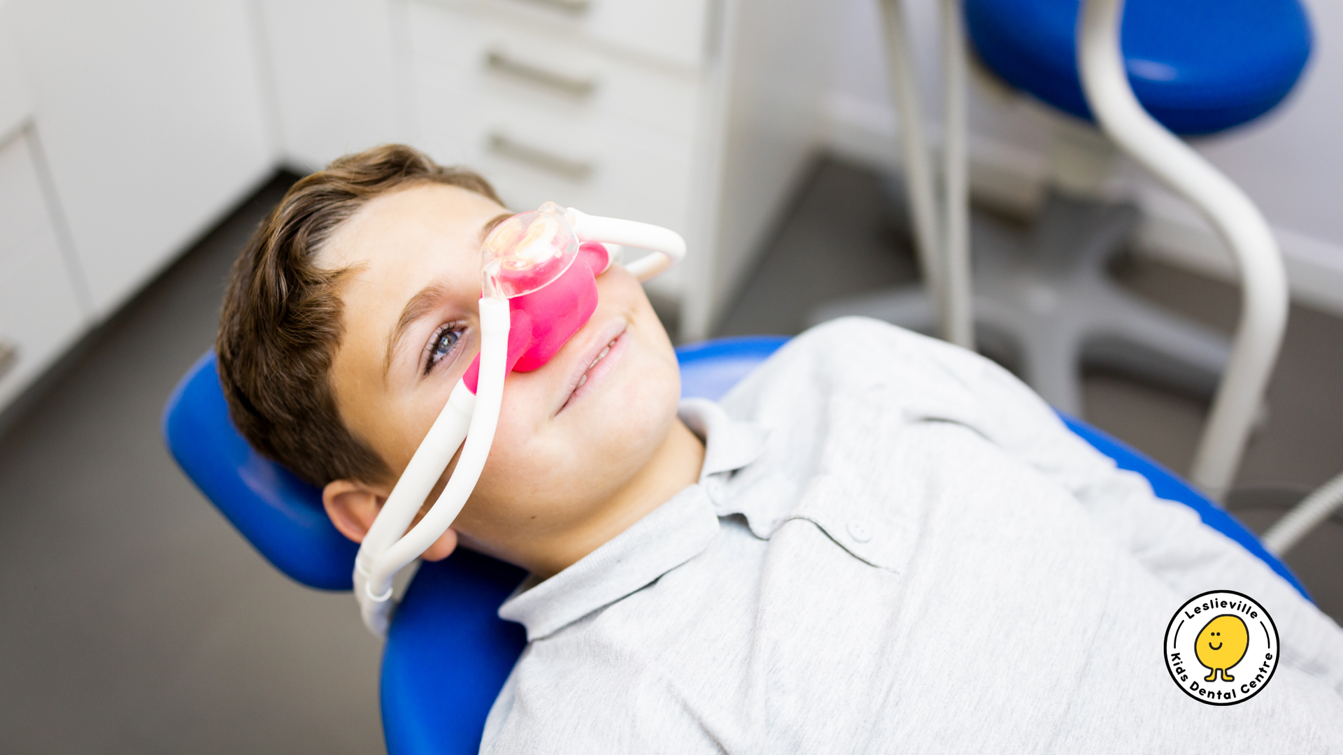A young boy is laying in a dental chair with an oxygen mask on his face.