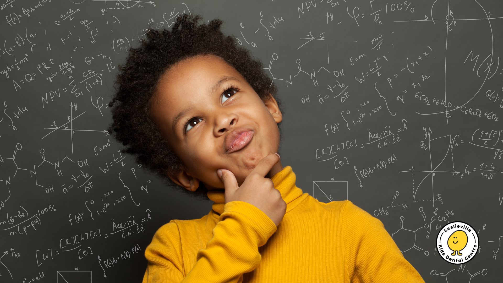 A young boy is thinking in front of a blackboard.