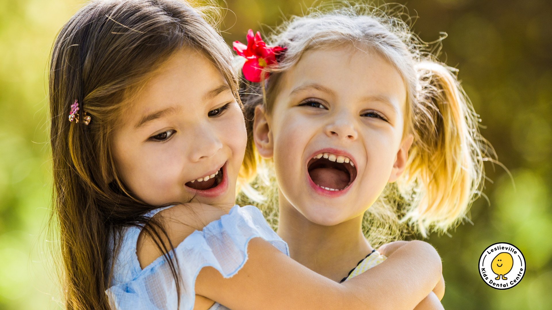 Two little girls are hugging each other and laughing.