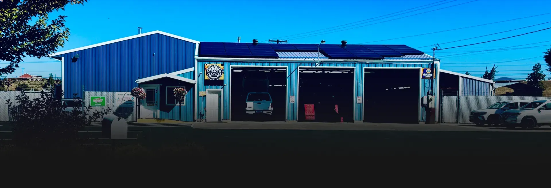 Blue auto repair shop with garage bays, a car inside, and a person in the foreground  | AJM Automotive Services LLC