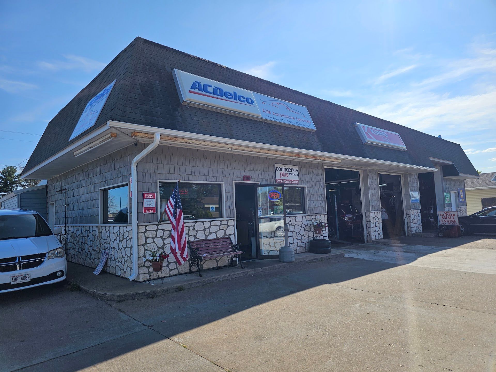 Auto repair shop exterior with AC Delco sign, brick-like facade, American flag, and garage bays  | AJM Automotive Services LLC