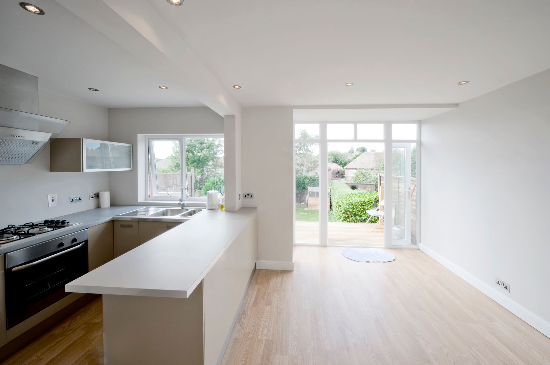 An empty kitchen with stainless steel appliances and wooden floors