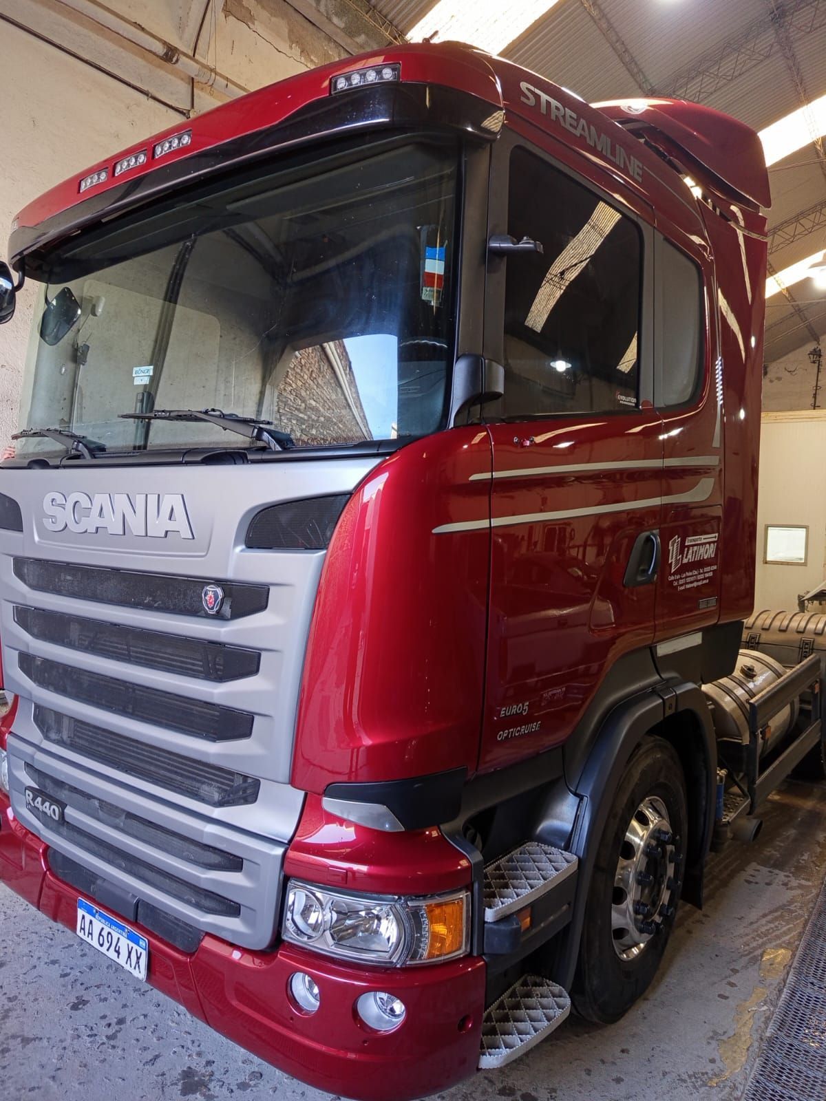 Cabina de camión Scania roja y plateada en un garaje.