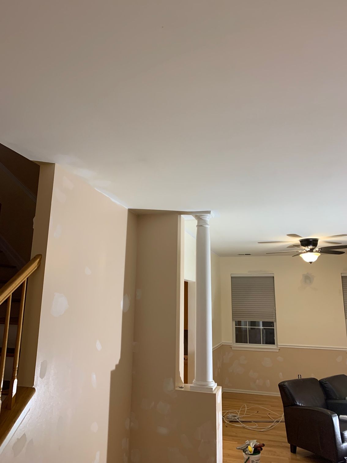 A living room with a couch , chair , stairs and a ceiling fan.