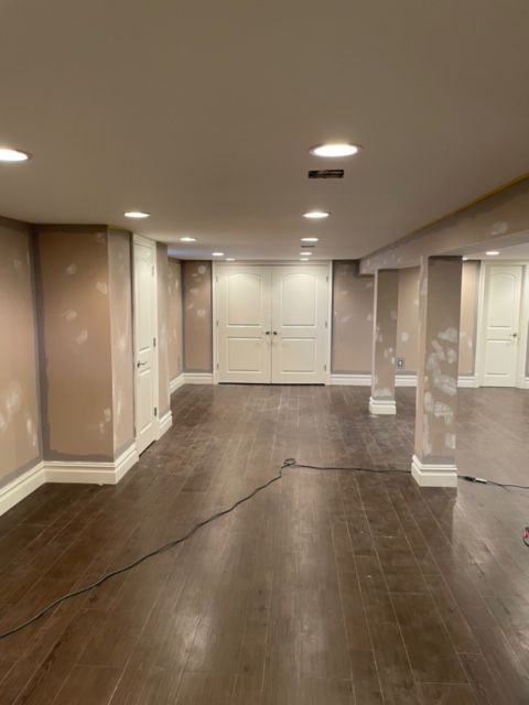 An empty basement with hardwood floors and white walls