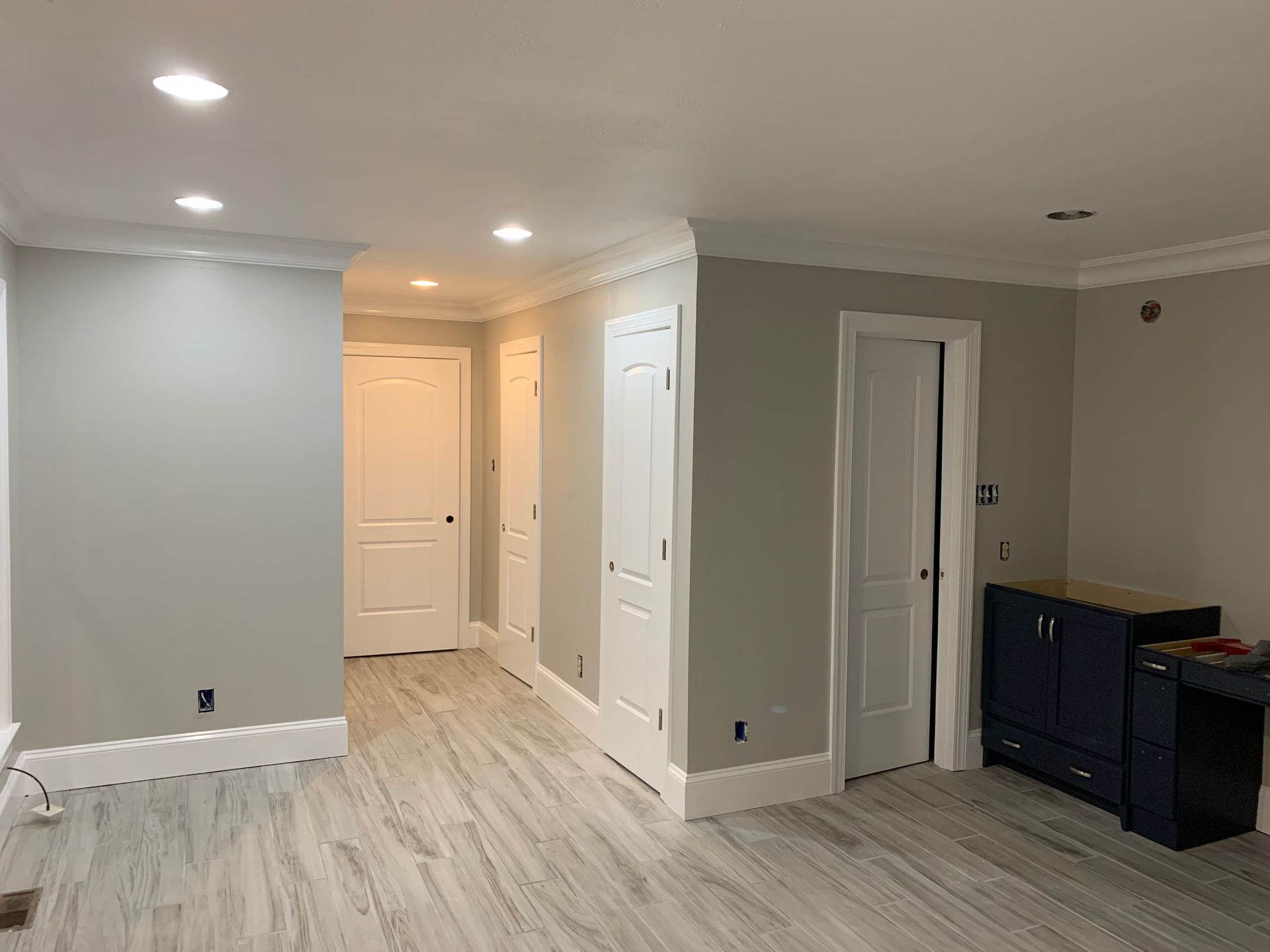A living room with hardwood floors , gray walls and white doors.