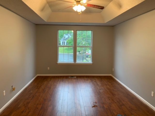 An empty room with hardwood floors and a ceiling fan