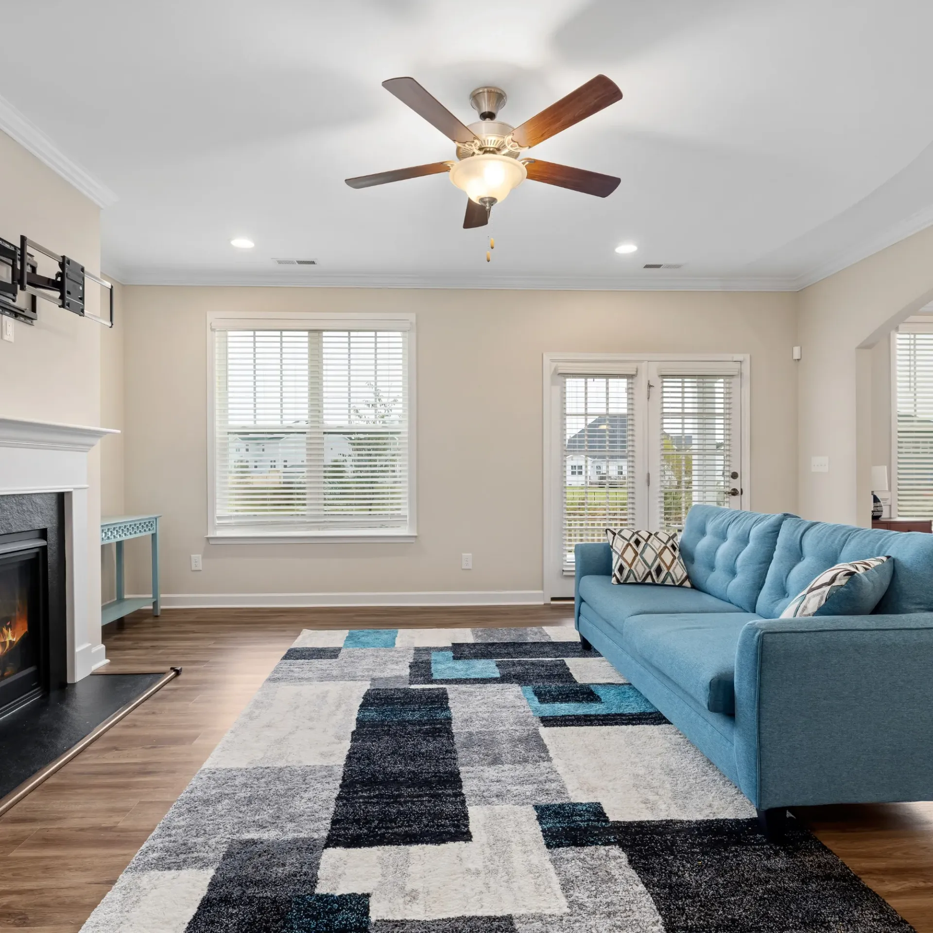 Horizon Electric USA - A living room with a blue couch , fireplace , rug and ceiling fan.