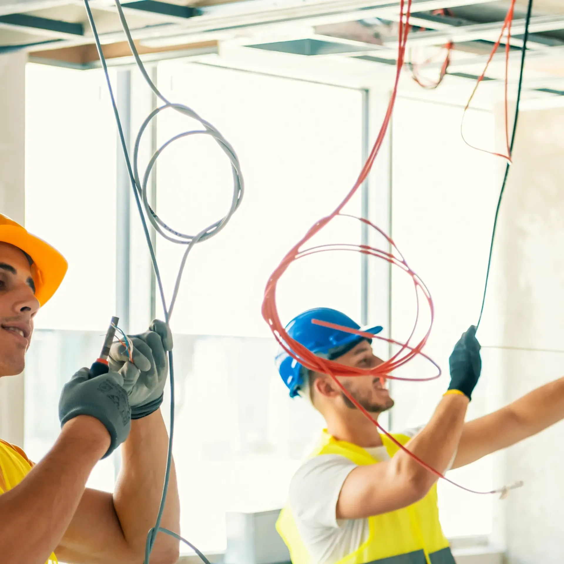 Horizon Electric USA - Two men are working on electrical wires hanging from the ceiling.