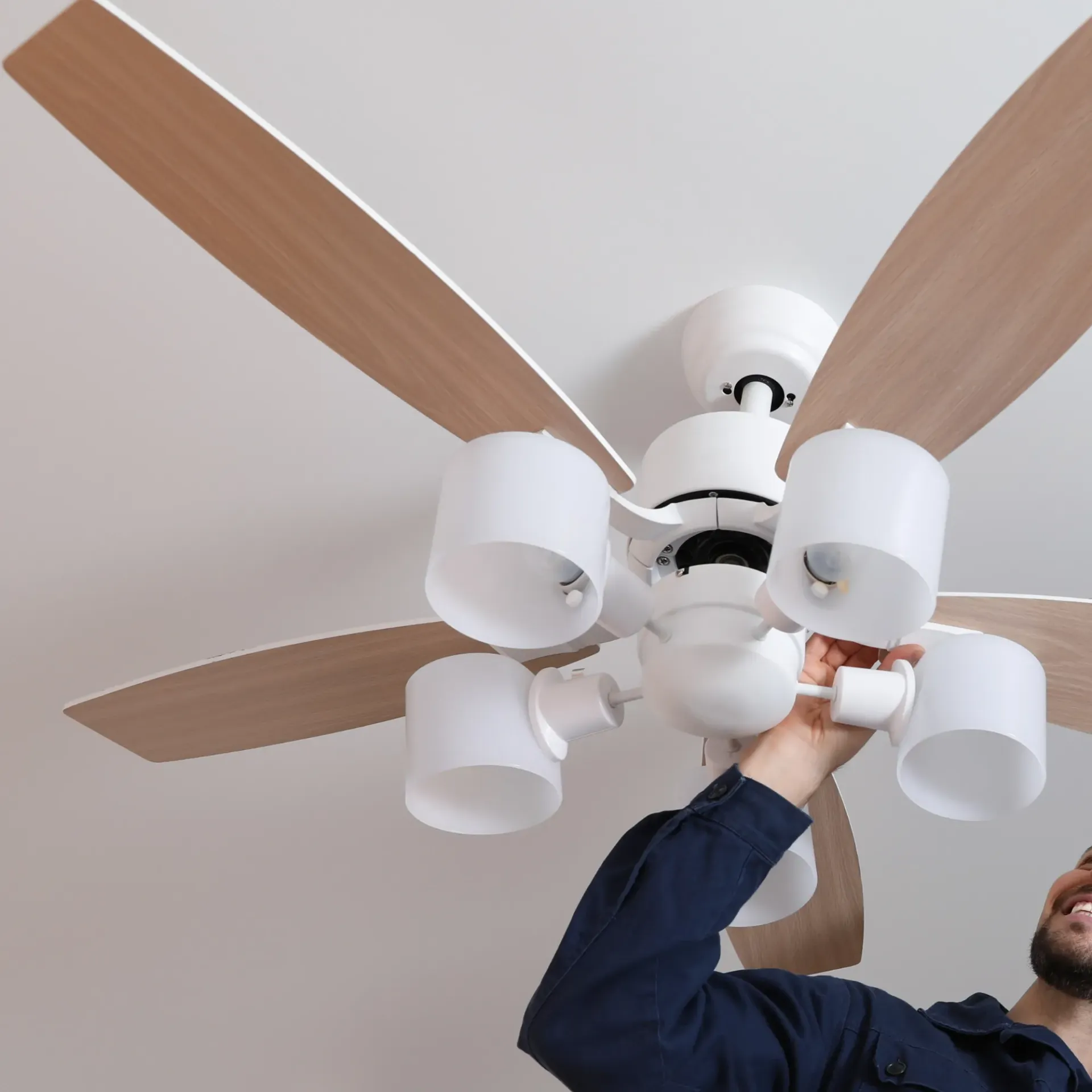 Horizon Electric USA - A man is fixing a ceiling fan with wooden blades