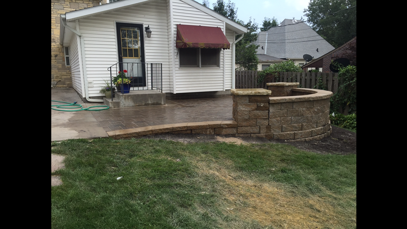 A small white house with a patio and a fire pit in front of it.