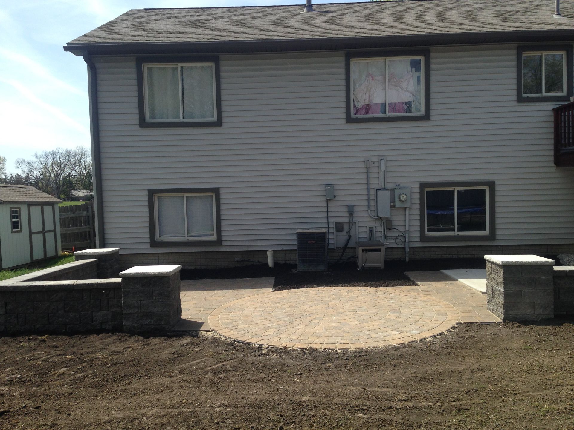 The back of a house with a patio in front of it.
