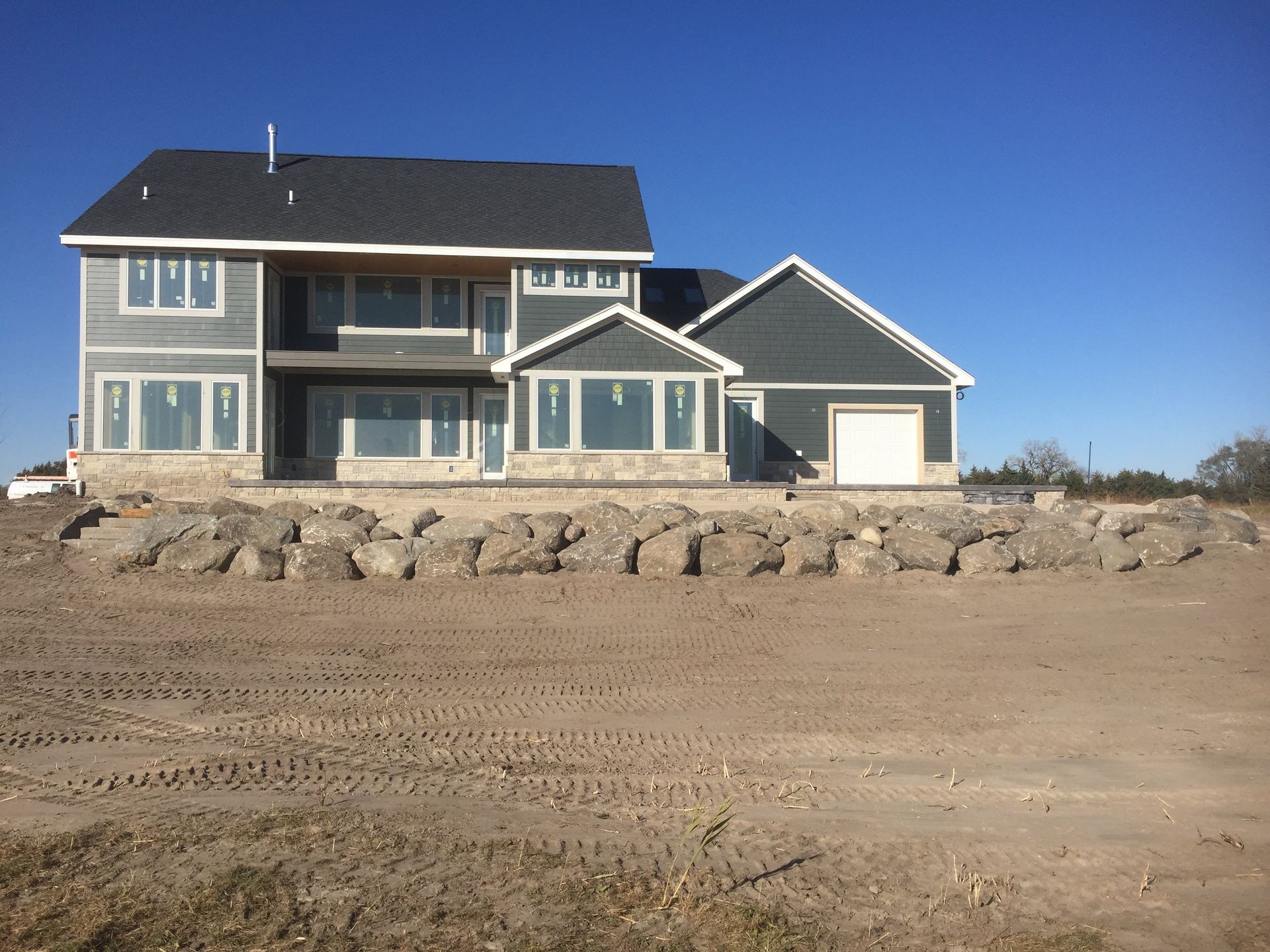 A large house sits in the middle of a dirt field