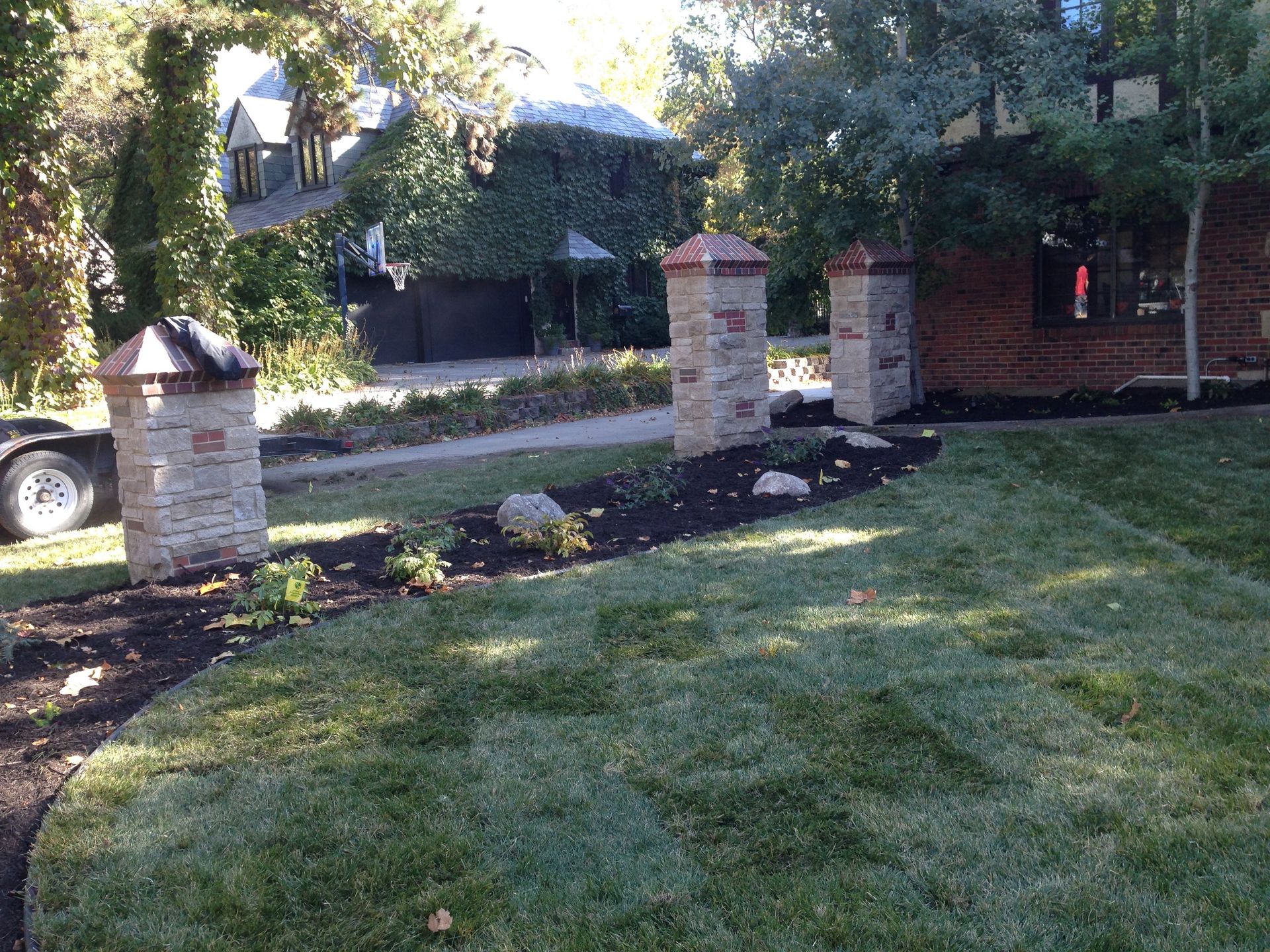 A lush green lawn with brick pillars in front of a house.