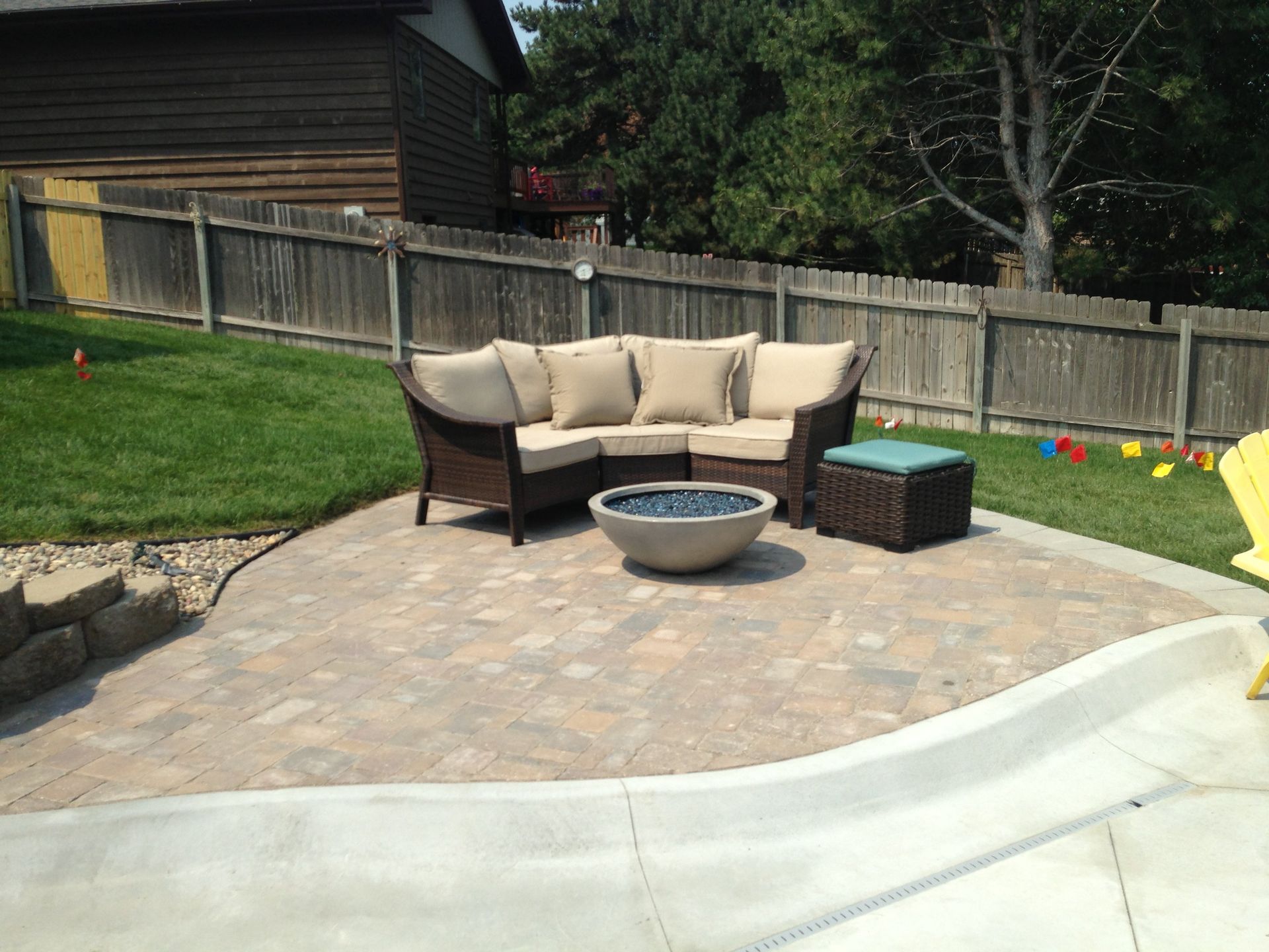 A patio with a sectional couch and a fire pit
