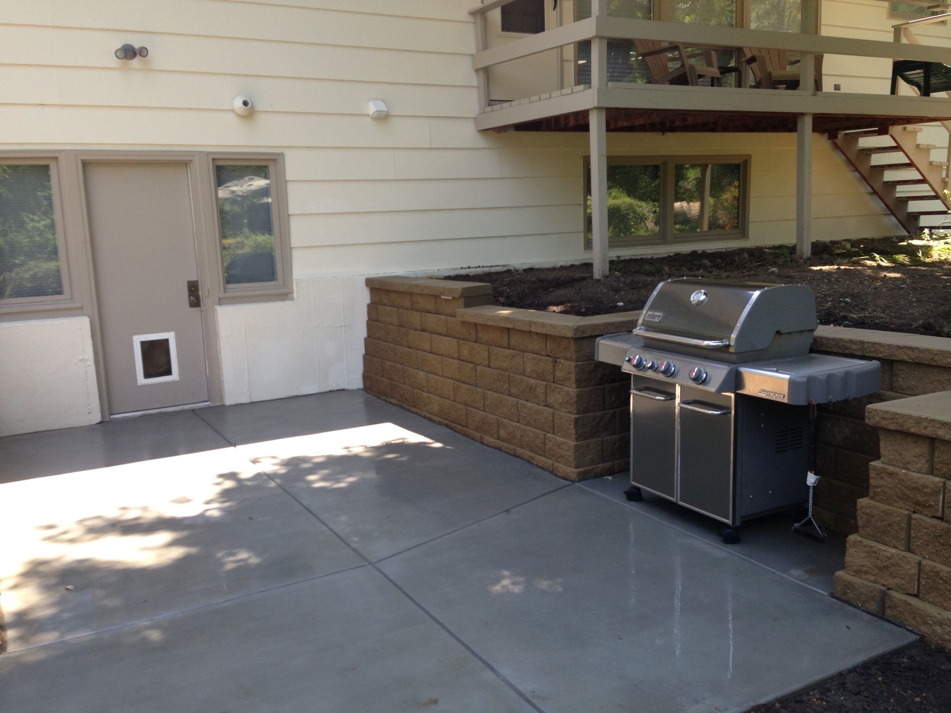 A grill is sitting on a patio in front of a house.