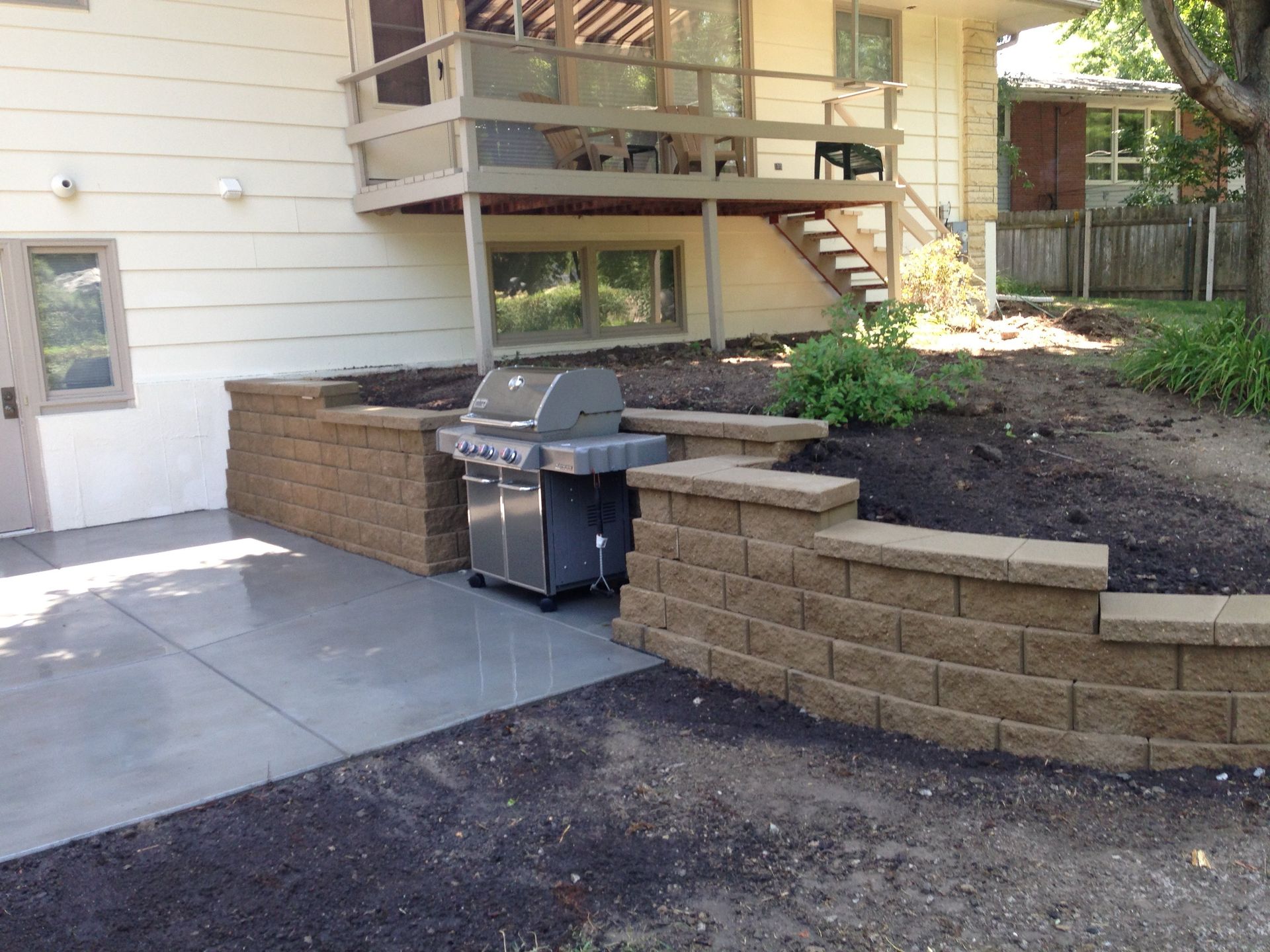 A grill is sitting on a patio in front of a house.
