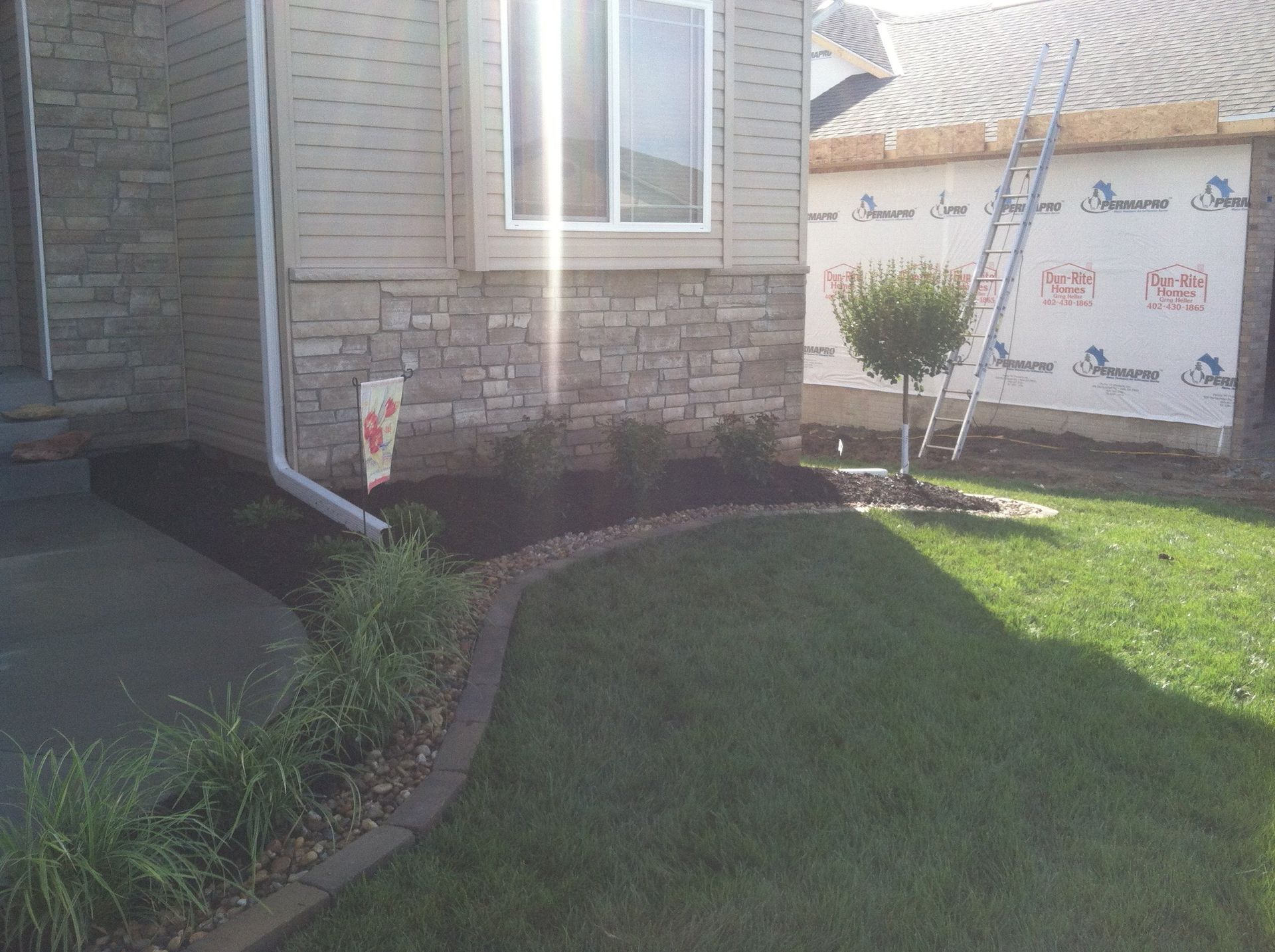 A house with a ladder on the side of it and a lawn in front of it.