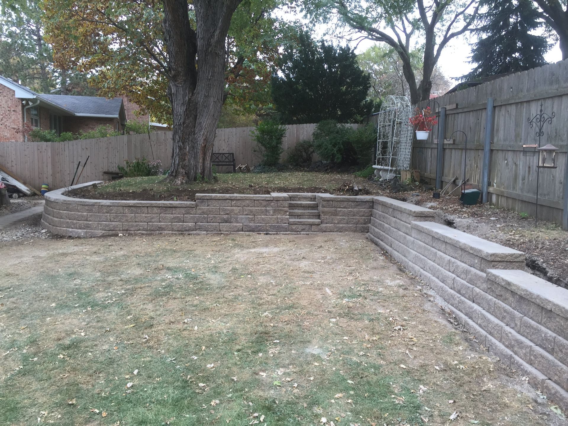 A backyard with a brick wall and a wooden fence.