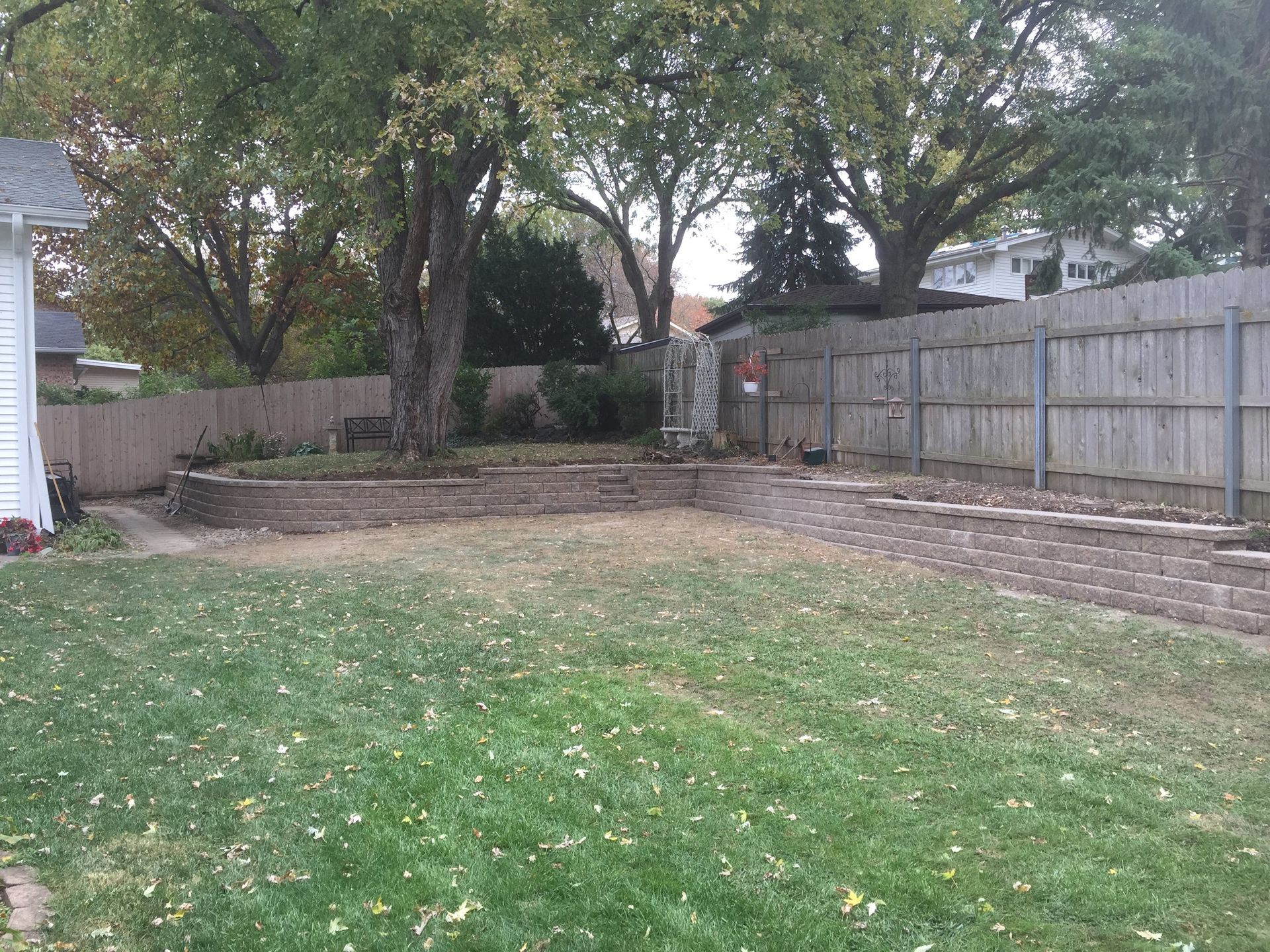 A backyard with a wooden fence and a lush green lawn.