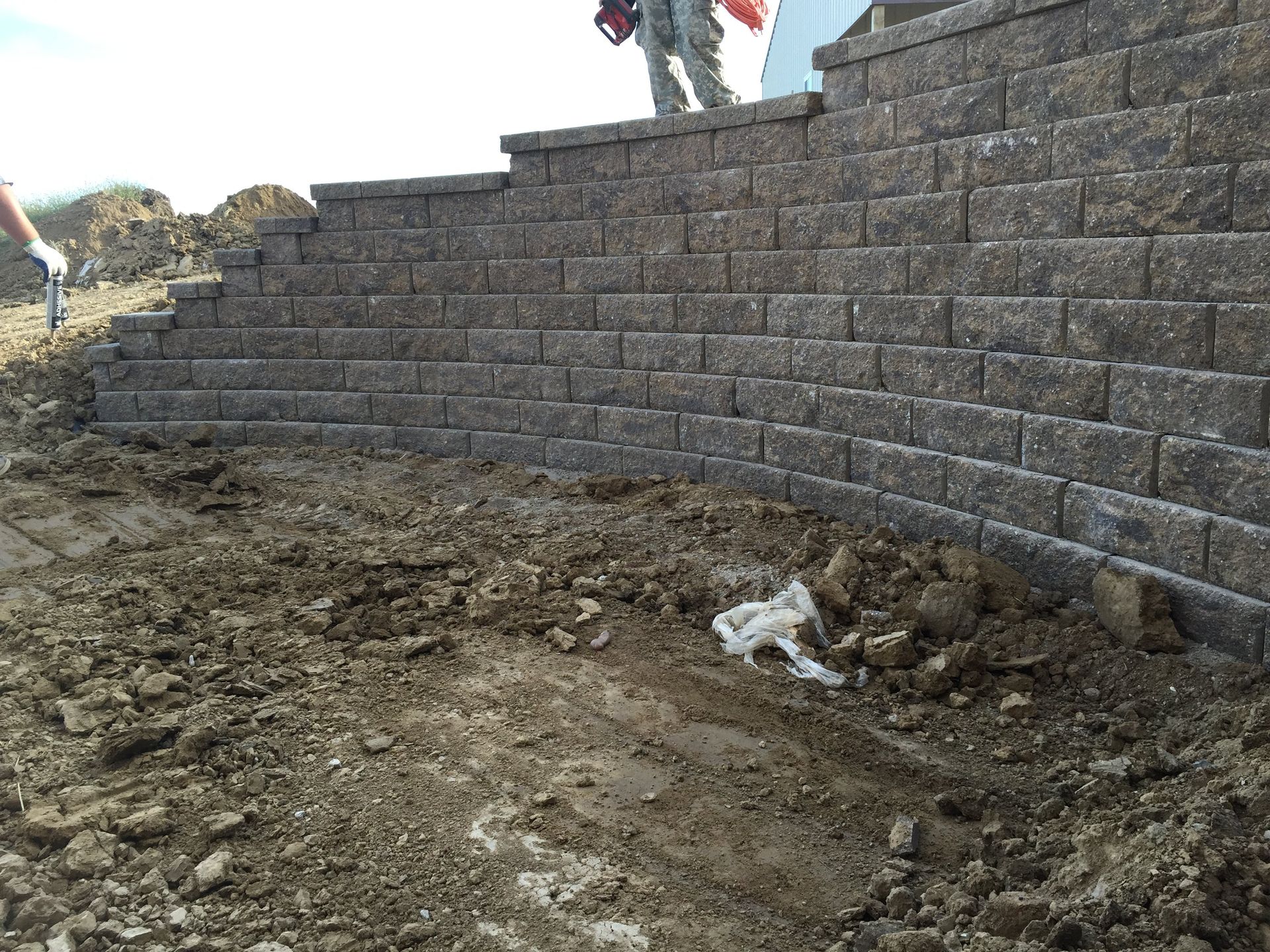 A brick wall is being built on top of a dirt field.