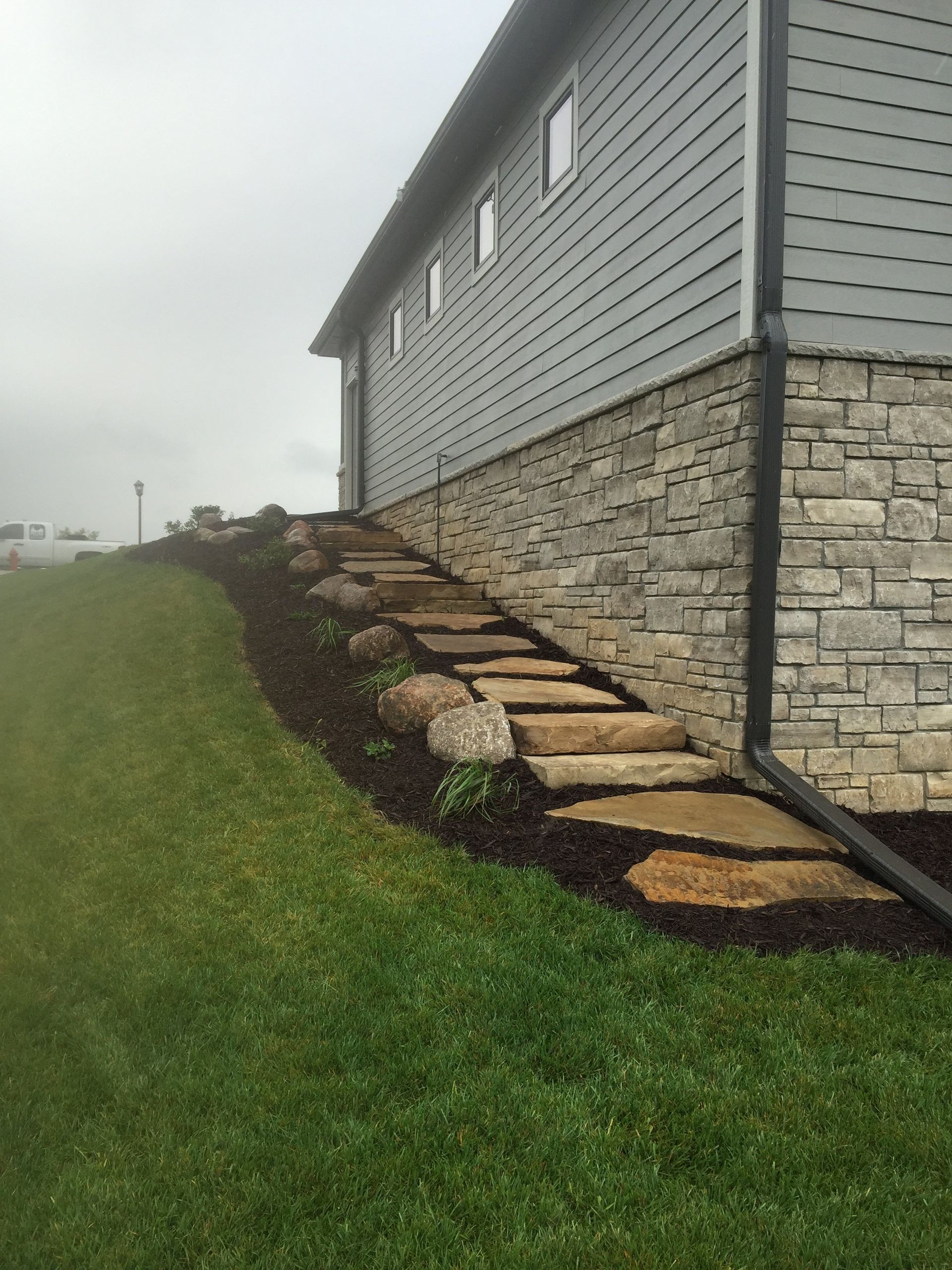 A stone walkway leading to the side of a house.